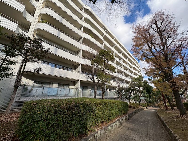 緑豊かな住環境に佇む開放的なマンション。歩道沿いの整った植栽が四季の移ろいを感じさせ、落ち着いた住まいの雰囲気を演出します。