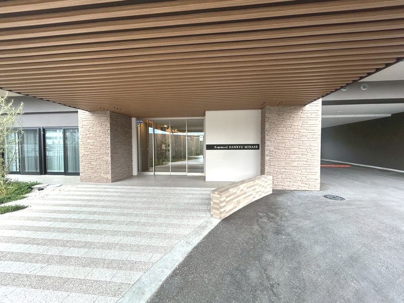 【CASA】ブランニード阪急水無瀬 ■現地■洗練された石積み調の外壁と開放的なガラス扉が魅力的。住まいの顔となるエントランスは、訪れる人を温かく迎え、日々の暮らしに安心と上質さをもたらします。