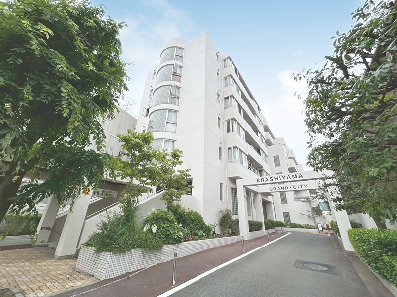 嵐山グランドシティ 緑豊かな環境に佇むマンション。アプローチからのびやかな曲線を描く外観が目を引きます。